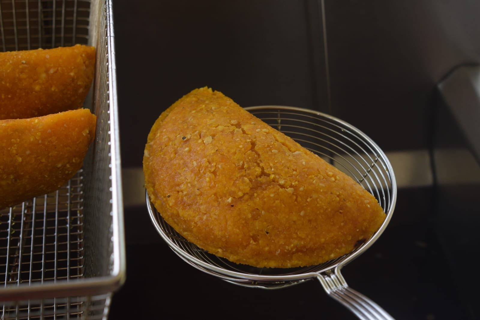 Empanada recién frita sobre la araña, dorada y crocante